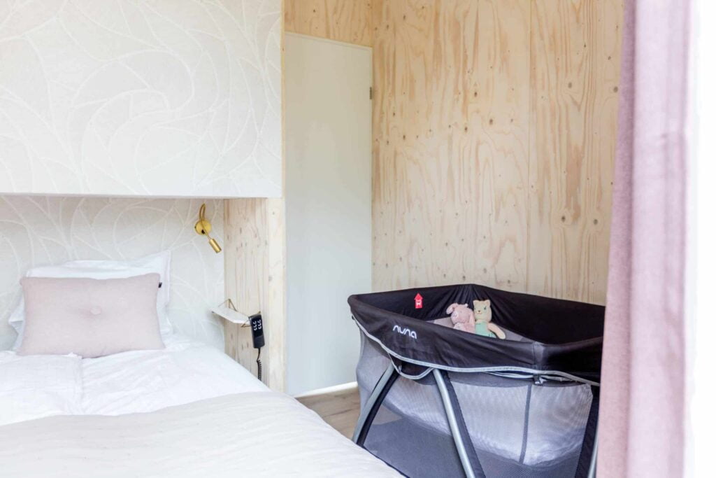 Wieg naast het bed in Tiny House Onyx, ideaal voor jonge gezinnen met een baby