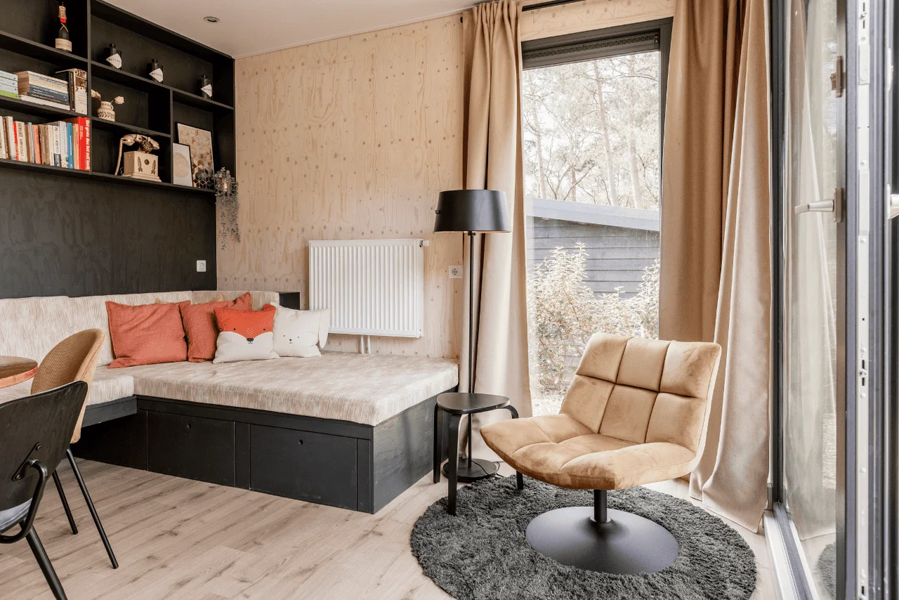 Woonkamer met comfortabele stoel, daybed en boeken in Tiny House Onyx op de Veluwe