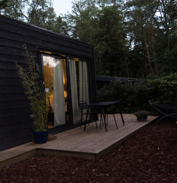 Romantische buitenkant van Tiny House Onyx in de avondzon, omgeven door natuur